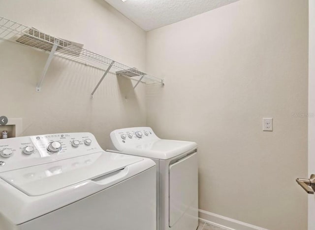 11807 Charades St, Orlando, FL 32832 - laundry room with separate washer and dryer, baseboards, and a textured ceiling