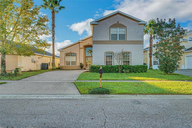 view of front of property featuring concrete driveway, a front yard, central air condition unit, and stucco siding