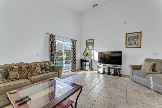 living room featuring a high ceiling, light tile patterned flooring, and baseboards