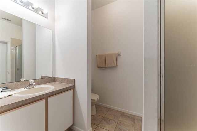 full bath featuring toilet, a stall shower, vanity, baseboards, and tile patterned floors
