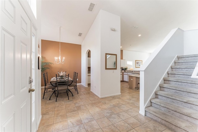 entrance foyer with stairway, arched walkways, a chandelier, baseboards, and high vaulted ceiling