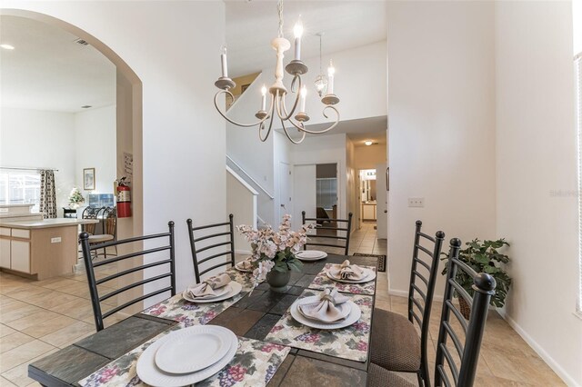 dining space with arched walkways, a high ceiling, light tile patterned flooring, a chandelier, and baseboards