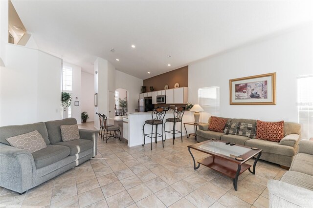 living area featuring a high ceiling, arched walkways, and recessed lighting