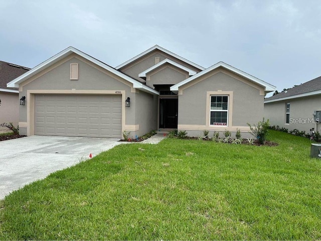 ranch-style house with an attached garage, stucco siding, a front yard, and driveway