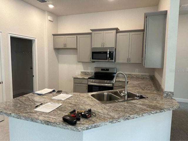 kitchen featuring appliances with stainless steel finishes, gray cabinets, a sink, a peninsula, and recessed lighting