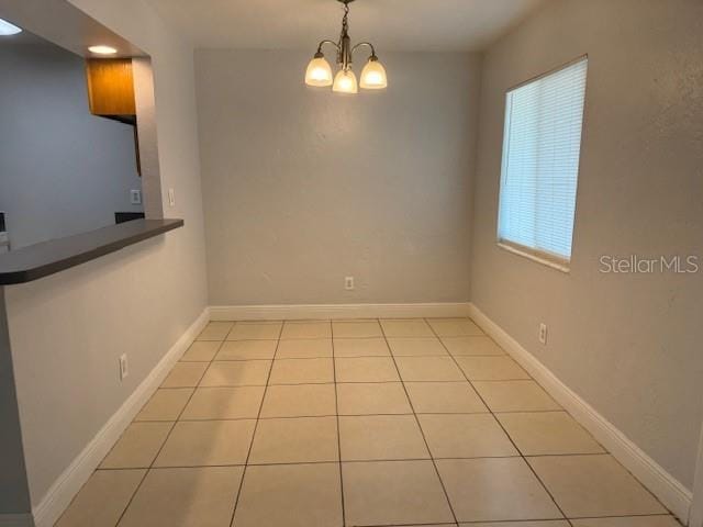 900 S Peninsula Dr Unit 208, Daytona Beach, FL 32118 - unfurnished dining area with light tile patterned floors, a chandelier, and baseboards