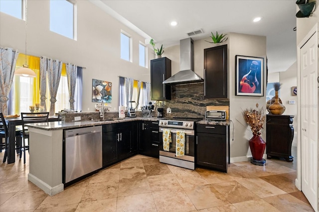 16 Sawfish Ct, Kissimmee, FL 34759 - kitchen with appliances with stainless steel finishes, wall chimney range hood, stone counters, a peninsula, and a sink