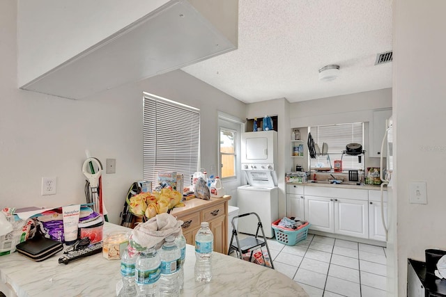 6524/6526 12th St W, Bradenton, FL 34207 - kitchen with stacked washer / drying machine, white cabinetry, a textured ceiling, and light tile patterned flooring