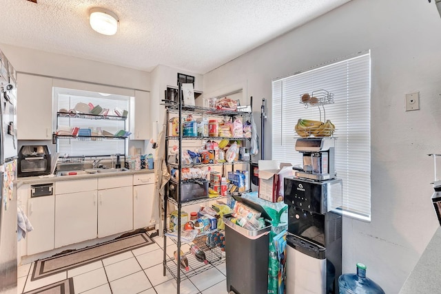 6524/6526 12th St W, Bradenton, FL 34207 - kitchen with a textured ceiling, white cabinetry, light tile patterned floors, a sink, and light countertops