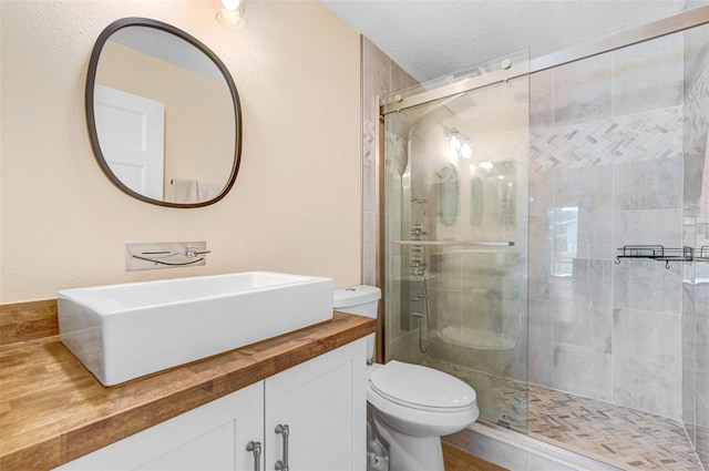 bathroom with a stall shower, toilet, and vanity
