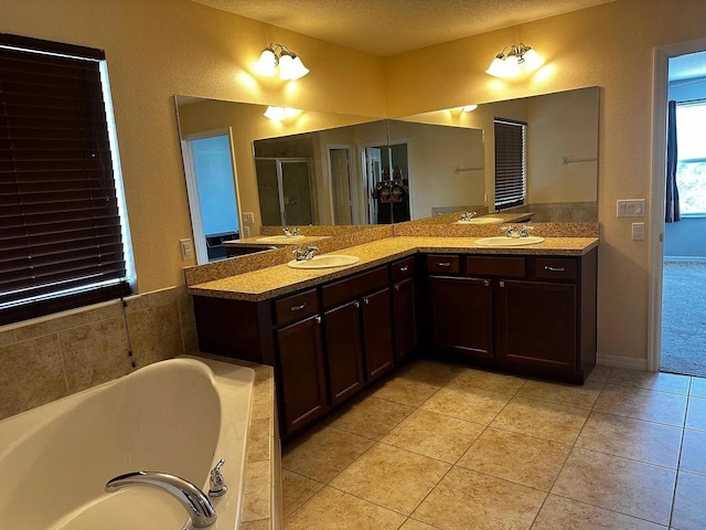 12610 Sawgrass Oak St, Orlando, FL 32824 - bathroom featuring tile patterned floors, a garden tub, double vanity, a textured ceiling, and a stall shower