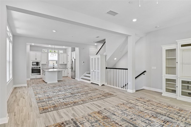 117 E Concord St Unit 7, Orlando, FL 32801 - unfurnished living room with light wood-type flooring, baseboards, a sink, and recessed lighting