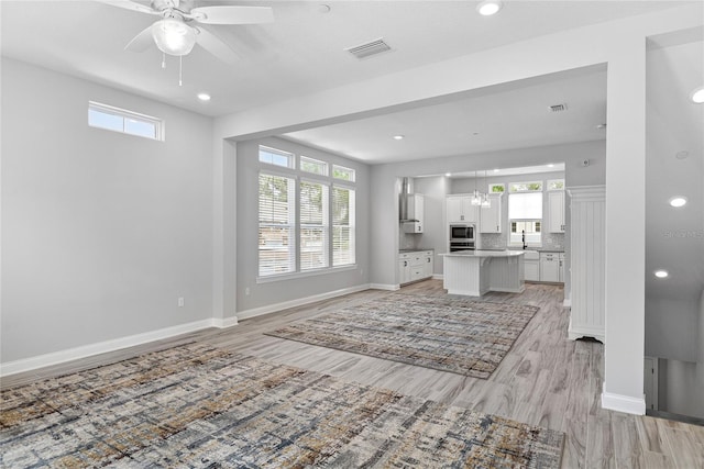 117 E Concord St Unit 7, Orlando, FL 32801 - unfurnished living room featuring ceiling fan, light wood finished floors, healthy amount of natural light, baseboards, and recessed lighting