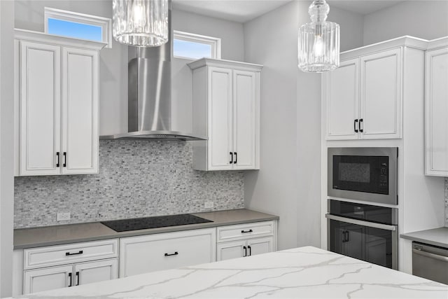 117 E Concord St Unit 7, Orlando, FL 32801 - kitchen with a chandelier, built in microwave, wall chimney exhaust hood, black electric cooktop, and decorative backsplash