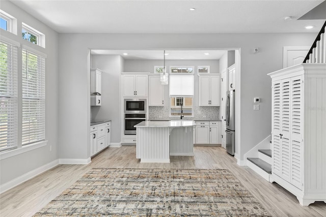 117 E Concord St Unit 7, Orlando, FL 32801 - kitchen featuring stainless steel appliances, light wood-style flooring, white cabinetry, a center island, and light countertops
