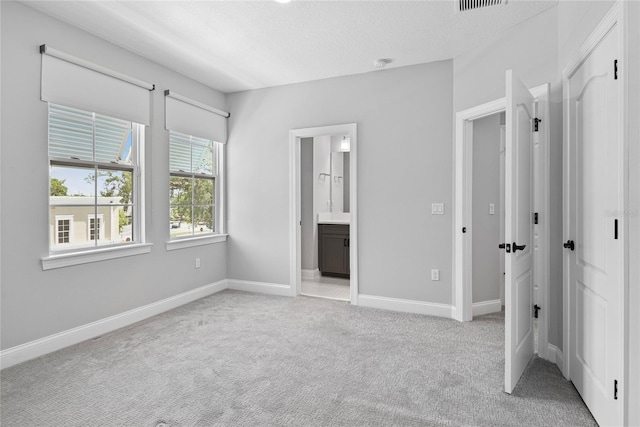 117 E Concord St Unit 7, Orlando, FL 32801 - unfurnished bedroom with light carpet, baseboards, ensuite bathroom, and a textured ceiling