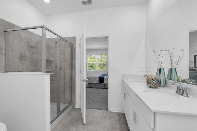 ensuite bathroom featuring a stall shower, tile patterned flooring, double vanity, and baseboards