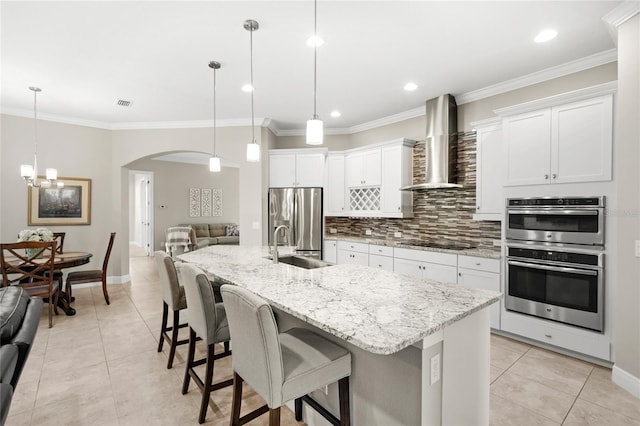 31754 Red Tail Blvd, Sorrento, FL 32776 - kitchen featuring wall chimney range hood, stainless steel appliances, a sink, light tile patterned flooring, and crown molding