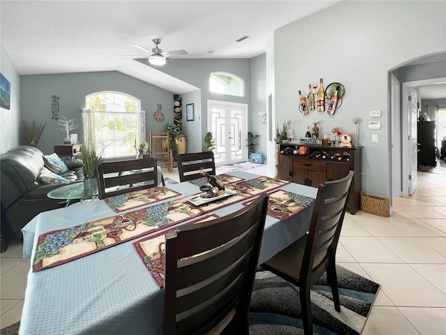 dining space with lofted ceiling, ceiling fan, arched walkways, healthy amount of natural light, and light tile patterned floors