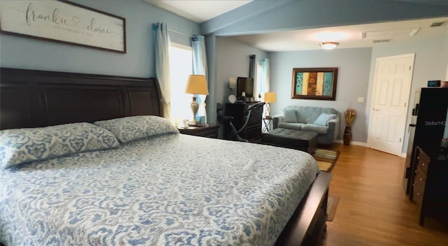bedroom with wood finished floors, baseboards, and vaulted ceiling