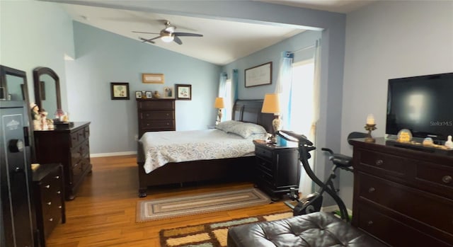 bedroom featuring wood finished floors, lofted ceiling, baseboards, and ceiling fan