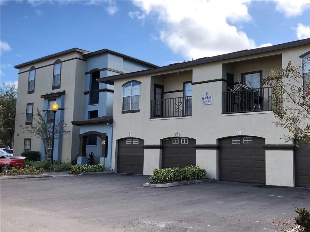 view of property featuring a garage, stucco siding, and driveway