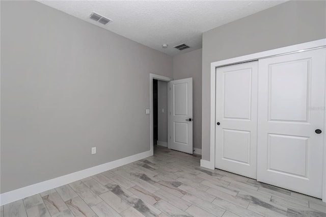 8202 SW 123rd Ter, Dunnellon, FL 34432 - unfurnished bedroom featuring a closet, a textured ceiling, baseboards, and light wood-type flooring