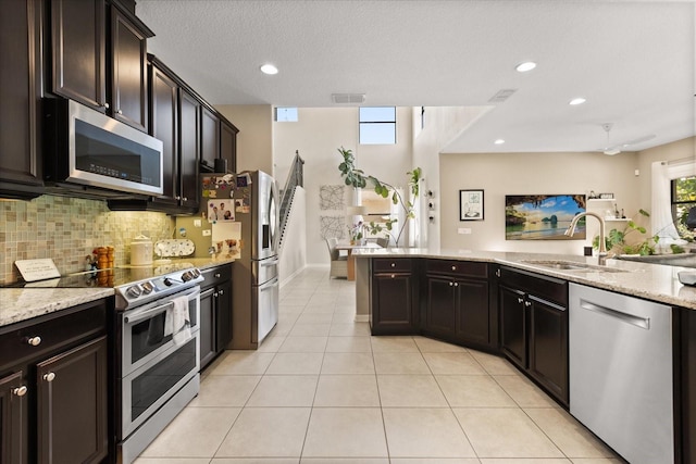 1501 Prairie Oaks Dr, Saint Cloud, FL 34771 - kitchen featuring appliances with stainless steel finishes, a sink, tasteful backsplash, light stone countertops, and recessed lighting