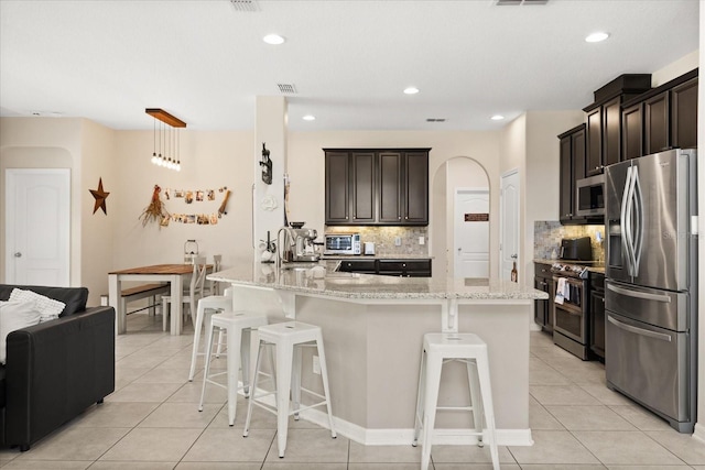 1501 Prairie Oaks Dr, Saint Cloud, FL 34771 - kitchen featuring stainless steel appliances, backsplash, light stone countertops, arched walkways, and recessed lighting