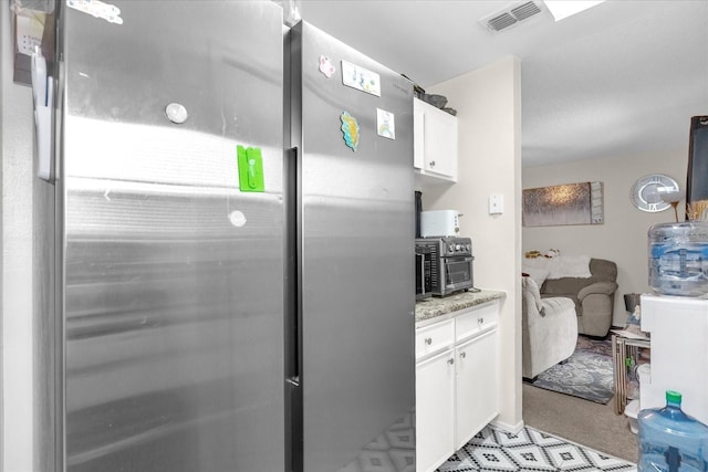 4160 Pershing Pointe Pl Unit 4, Orlando, FL 32822 - kitchen featuring freestanding refrigerator, white cabinets, light carpet, and light stone countertops