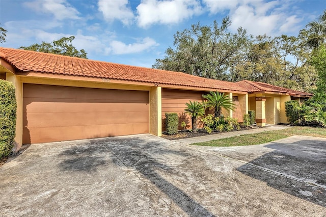 5039 Jamaica Cir Unit 10, Orlando, FL 32808 - view of front of property with an attached garage, concrete driveway, a tiled roof, and stucco siding