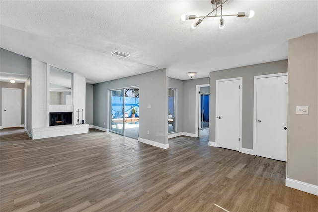 5039 Jamaica Cir Unit 10, Orlando, FL 32808 - unfurnished living room featuring a textured ceiling, wood finished floors, a chandelier, baseboards, and a brick fireplace