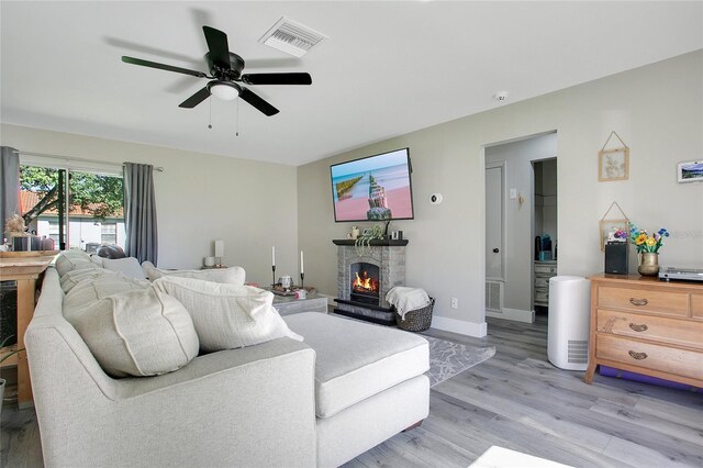 10148 Eventide Ct, Orlando, FL 32821 - living area with a fireplace, light wood-style flooring, a ceiling fan, and baseboards