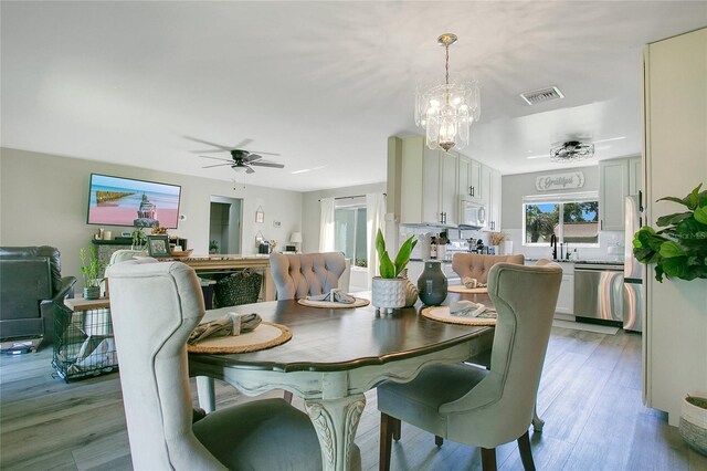 10148 Eventide Ct, Orlando, FL 32821 - dining space with ceiling fan, light wood-style floors, and a chandelier
