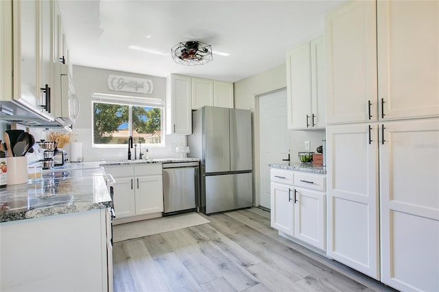 10148 Eventide Ct, Orlando, FL 32821 - kitchen with appliances with stainless steel finishes, a sink, light wood-style floors, light stone counters, and white cabinetry