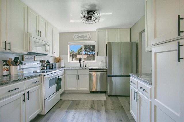 10148 Eventide Ct, Orlando, FL 32821 - kitchen with appliances with stainless steel finishes, a sink, light wood-type flooring, and light stone counters