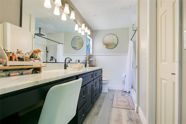 10148 Eventide Ct, Orlando, FL 32821 - full bathroom with wood finished floors, wainscoting, double vanity, a shower with shower curtain, and toilet