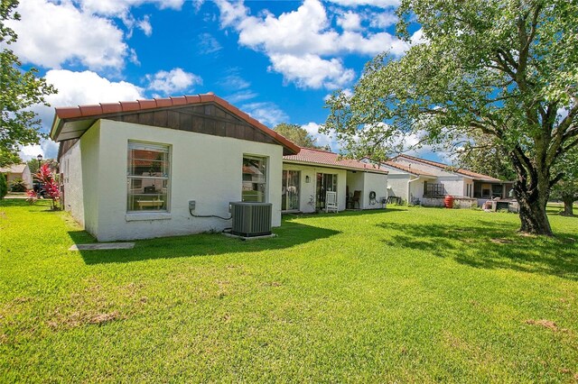 10148 Eventide Ct, Orlando, FL 32821 - back of property with central AC, a tile roof, stucco siding, and a lawn