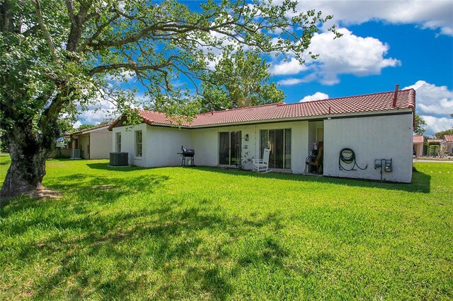 10148 Eventide Ct, Orlando, FL 32821 - back of property featuring a tile roof, stucco siding, a lawn, and cooling unit