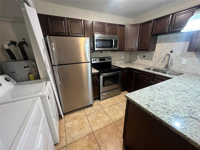 51 Windtree Ln Unit 101, Winter Garden, FL 34787 - kitchen featuring appliances with stainless steel finishes, a sink, washing machine and dryer, dark brown cabinetry, and water heater