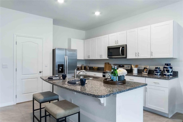 1302 Isleta Loop, Kissimmee, FL 34741 - kitchen with stainless steel appliances, a sink, white cabinets, a kitchen bar, and light tile patterned floors
