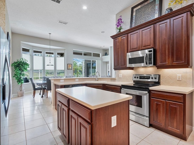 3840 Caledonia Ave, Apopka, FL 32712 - kitchen with stainless steel appliances, light countertops, a peninsula, tasteful backsplash, and light tile patterned flooring