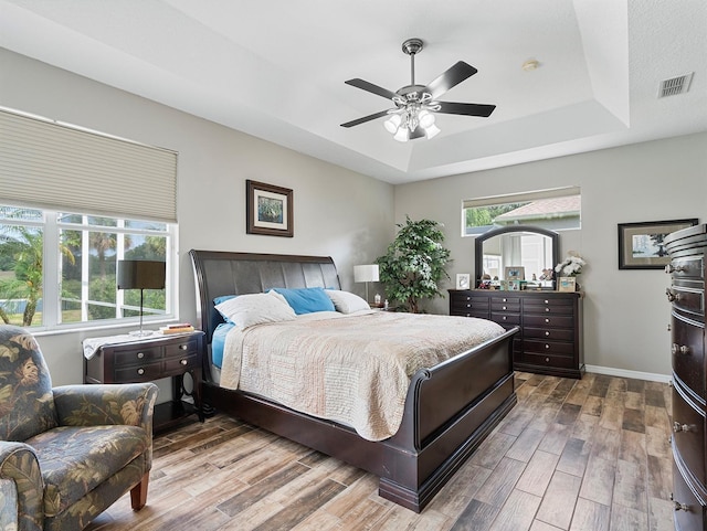 3840 Caledonia Ave, Apopka, FL 32712 - bedroom featuring a tray ceiling, wood finished floors, baseboards, and a ceiling fan
