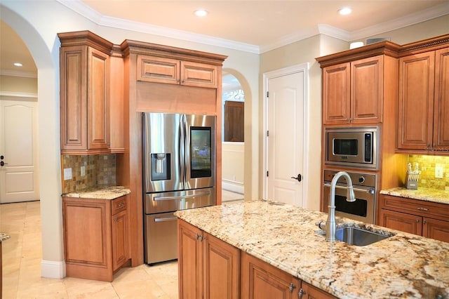 11013 Ullswater Ln, Windermere, FL 34786 - kitchen featuring appliances with stainless steel finishes, arched walkways, a sink, light stone countertops, and crown molding