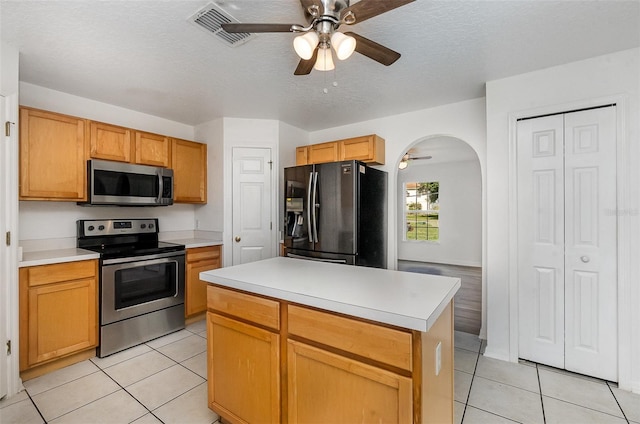 kitchen with stainless steel appliances, ceiling fan, light tile patterned floors, light countertops, and a textured ceiling
