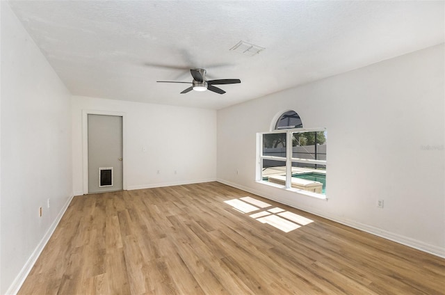spare room featuring light wood-type flooring, ceiling fan, and baseboards