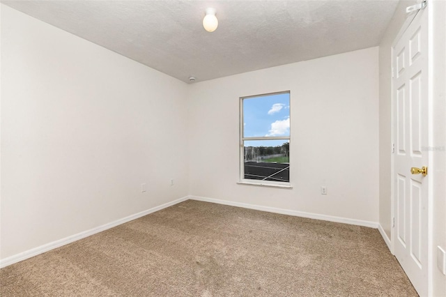 carpeted empty room featuring baseboards and a textured ceiling