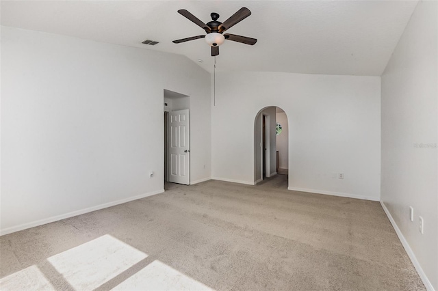carpeted spare room featuring arched walkways, a ceiling fan, vaulted ceiling, and baseboards
