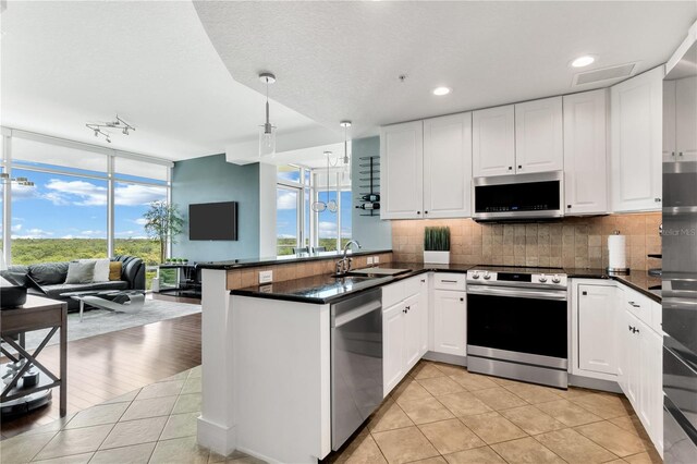 101 S Eola Dr Unit 810, Orlando, FL 32801 - kitchen with appliances with stainless steel finishes, open floor plan, a peninsula, backsplash, and floor to ceiling windows