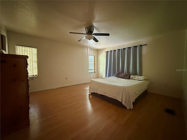 bedroom with wood finished floors, baseboards, ceiling fan, and a textured ceiling